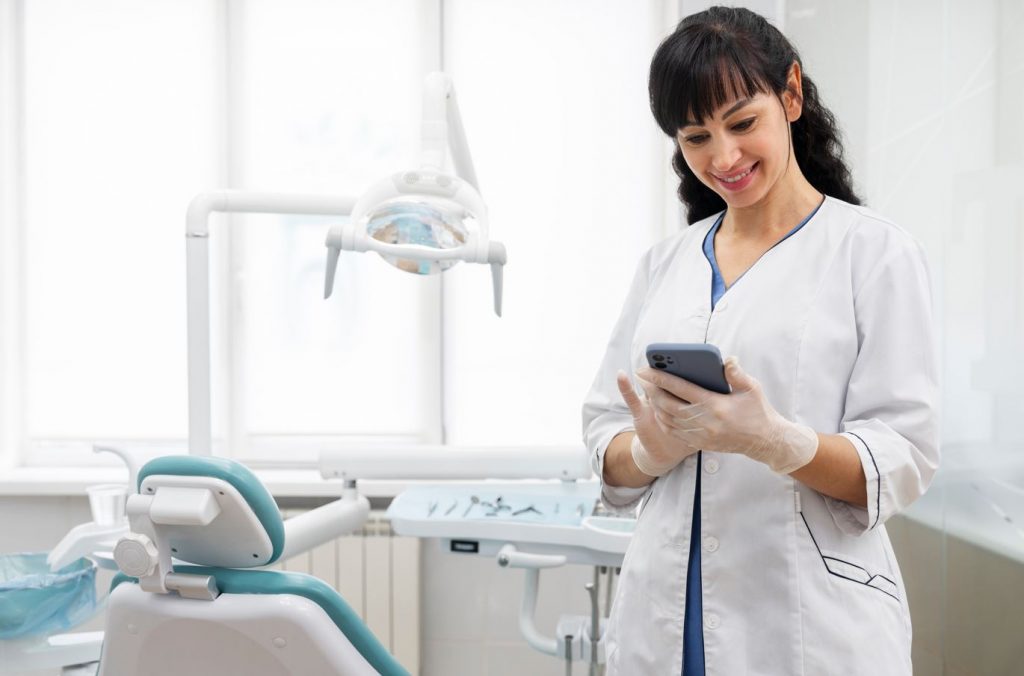 Dentista em consultório utilizando seu smartphone