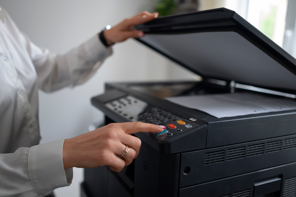Mãos de empresária apertando o botão de uma scanner para digitalizar um documento.