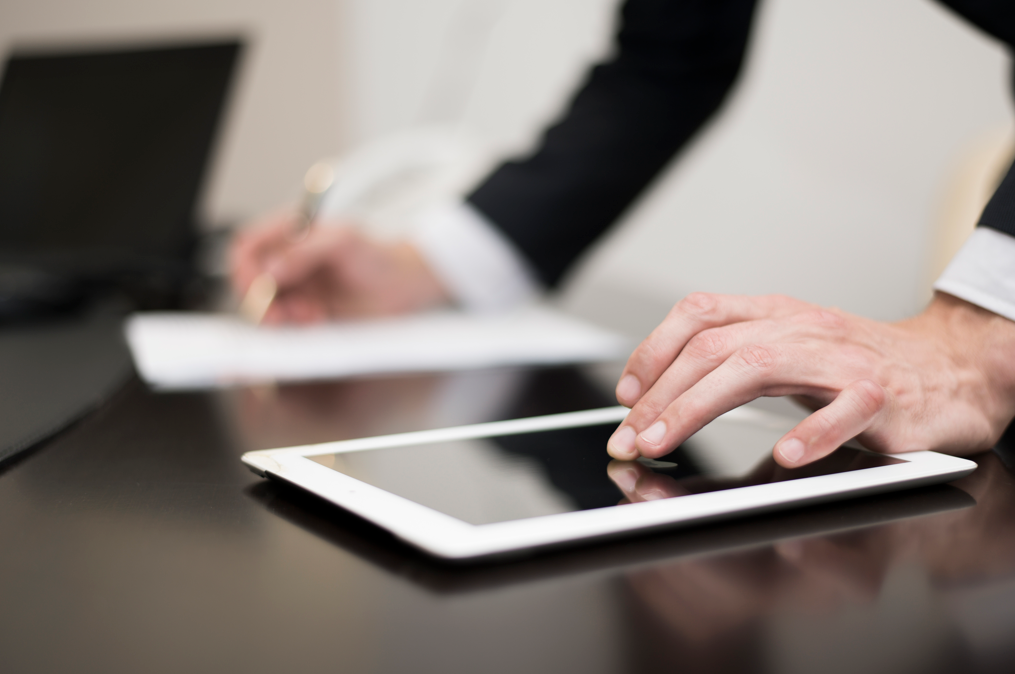 Empresário assinando um papel e clicando em um tablet com um documento digitalizado