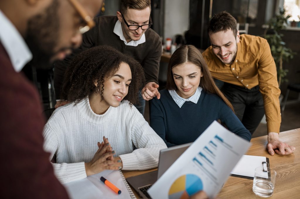 Grupo de pessoas reunidas em um escritório e analisando gráficos